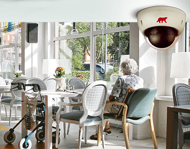 Care home restaurant with lady sitting at table and CCTV camera