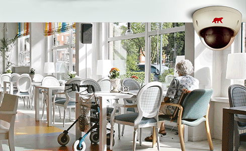 Care home restaurant with lady sitting at table and CCTV camera