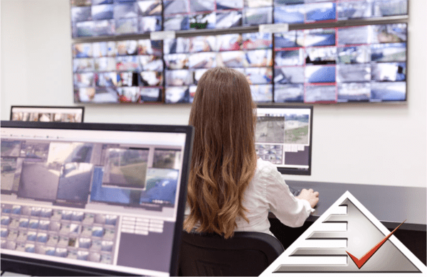 woman sitting in front of cctv monitoring screens with alertline logo