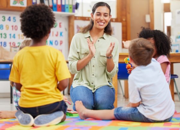 Nursery staff member and children, happy and playing