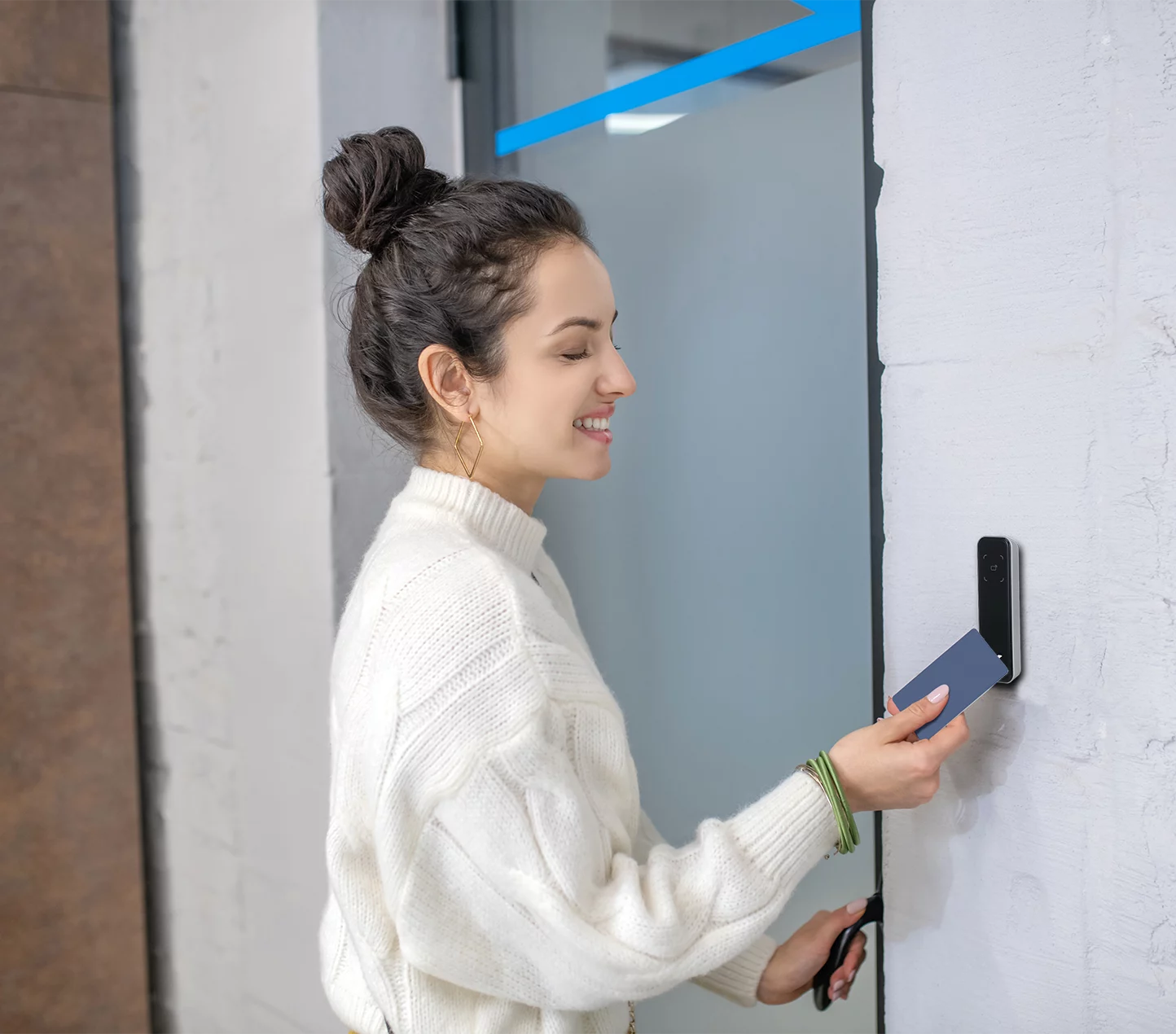 Young woman holding an access card to a fob reader to open the door